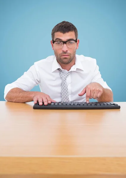 Hombre en gafas escribiendo en el teclado sobre fondo azul — Foto de Stock