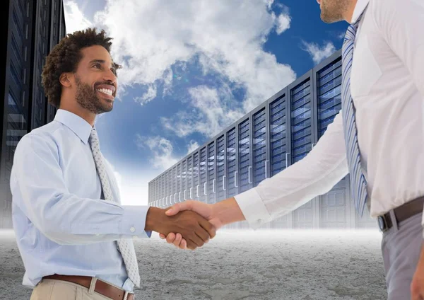 Empresario estrechando la mano entre sí y servidores contra el cielo en segundo plano —  Fotos de Stock