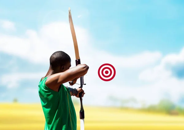 Man aiming with bow and arrow at target — Stock Photo, Image