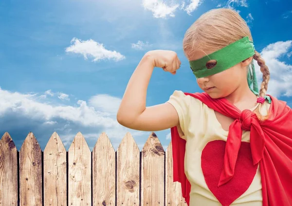 Girl in in superhero costume flexing her arms against sky in background — Stock Photo, Image