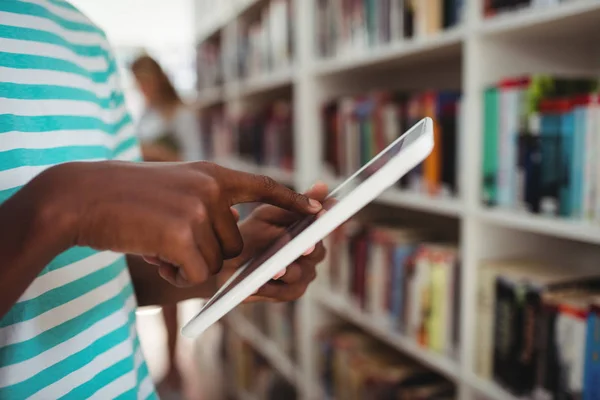 Skolpojke använda surfplatta i biblioteket — Stockfoto