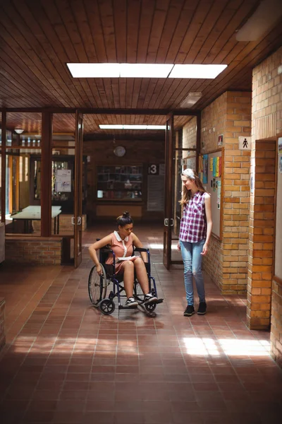 Schoolgirl talking with her disabled friend — Stock Photo, Image