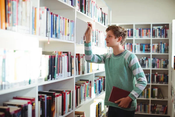 Uczeń wybierając książki w bibliotece — Zdjęcie stockowe