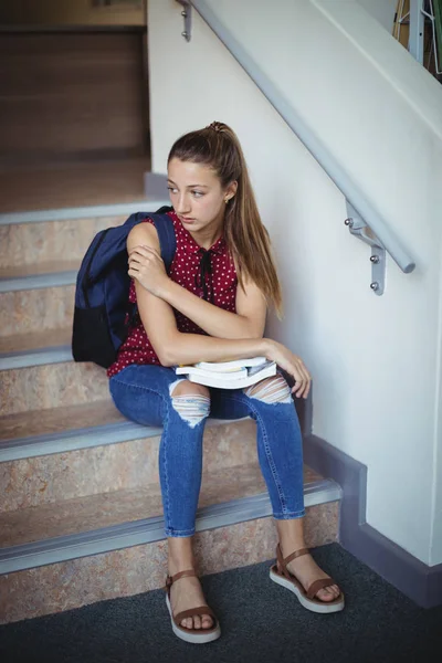 Sad schoolgirl sitting alone on staircase — Stock Photo, Image