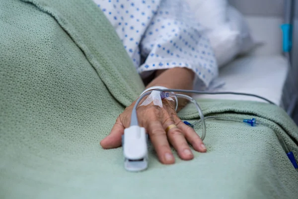 Senior patient hand with saline on bed in hospital — Stock Photo, Image