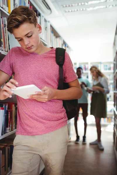 Aufmerksamer Schüler mit digitalem Tablet in Bibliothek — Stockfoto