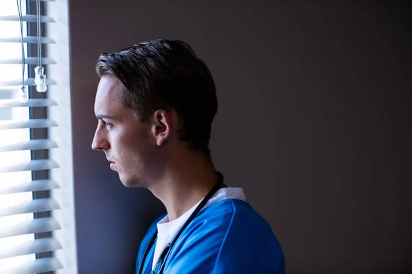 Omtänksamma läkare tittar genom fönstret — Stockfoto