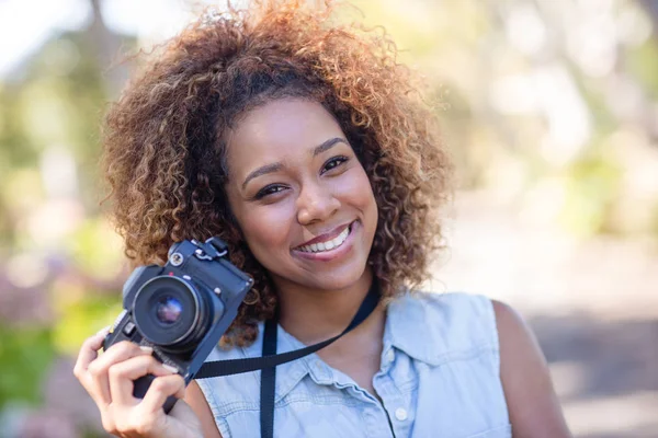 Mujer sonriente de pie con la cámara — Foto de Stock