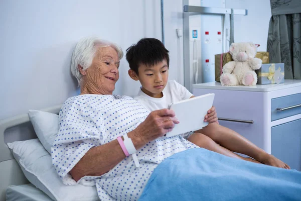 Äldre patienten och pojke håller digital tablett — Stockfoto