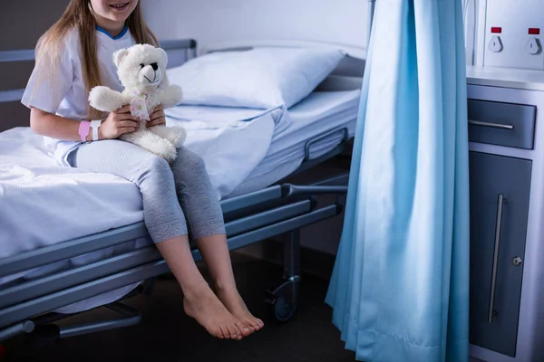 Пациент сидит с плюшевым мишкой на больничной койке — стоковое фото