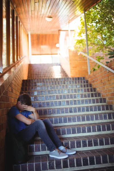 Triste colegial sentado solo en la escalera — Foto de Stock