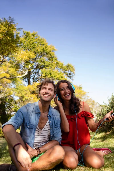 Couple listening to music in park — Stock Photo, Image