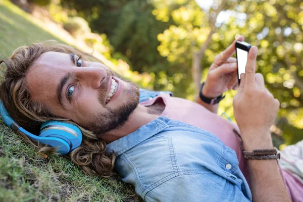 Homme allongé sur l'herbe écoutant de la musique — Photo