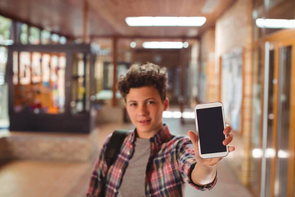 Schooljongen permanent met Schooltasje tonen van de telefoon — Stockfoto