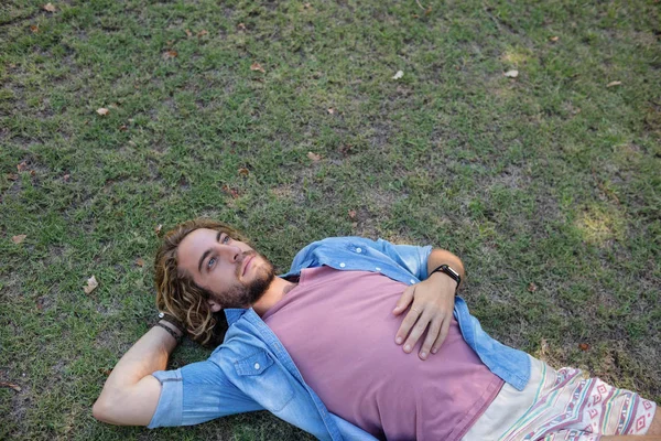 Продуманий чоловік лежить на траві — стокове фото