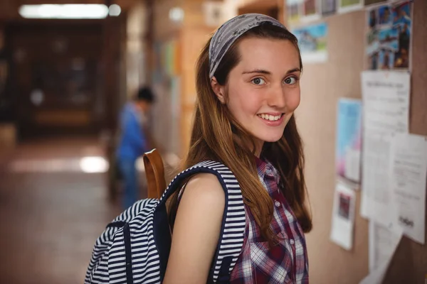 Улыбающаяся школьница, стоящая возле доски объявлений — стоковое фото