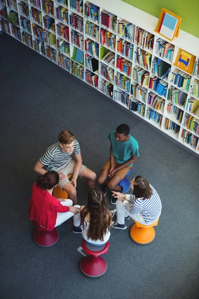 Estudiantes interactuando entre sí en la biblioteca —  Fotos de Stock
