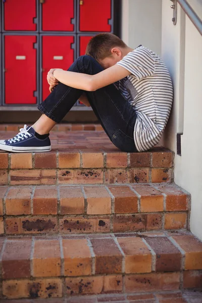 Sad schoolboy sitting on staircase — Stock Photo, Image