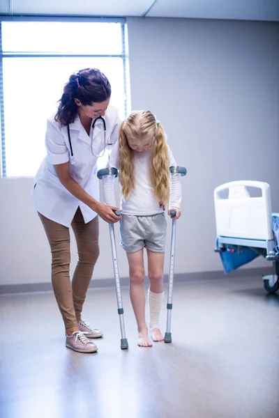 Orvos segíti a lányt, hogy séta a mankó — Stock Fotó