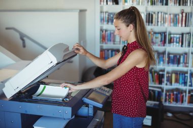 Attentive schoolgirl using Xerox photocopier clipart
