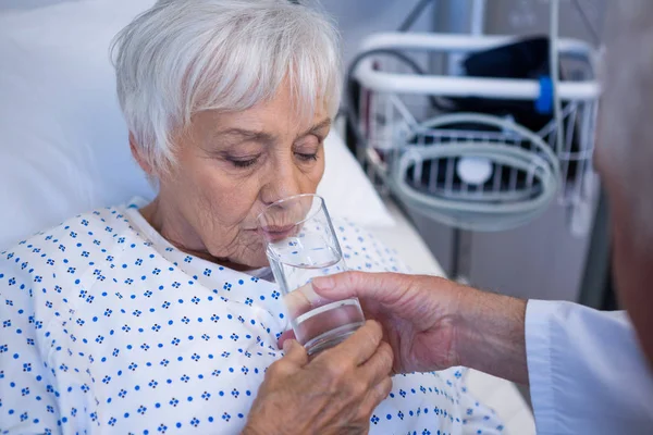 Dokter glas water geven aan patiënt — Stockfoto