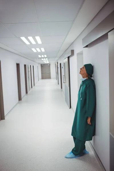 Tensed female surgeon leaning on wall — Stock Photo, Image