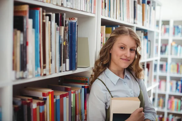 Schoolgirl holding book in library — Stock Photo, Image