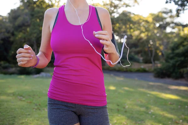 Female jogger listening to music while jogging — Stock Photo, Image