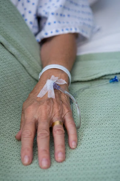 Senior patient hand with saline on bed — Stock Photo, Image