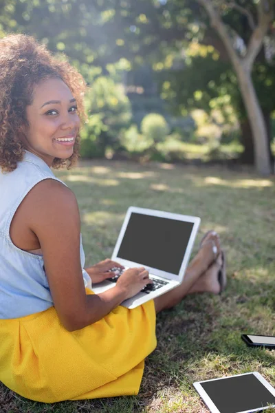 Mujer sentada en el parque y usando el ordenador portátil —  Fotos de Stock