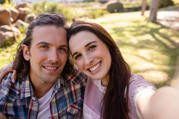 Casal clicando em uma selfie no parque — Fotografia de Stock