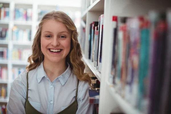 Lycklig Skolflicka stående i biblioteket — Stockfoto