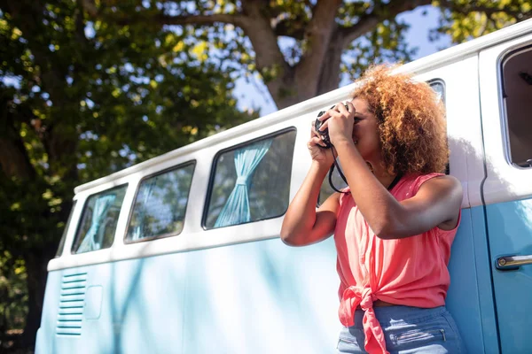 Woman leaning on campervan and photographing — Stock Photo, Image