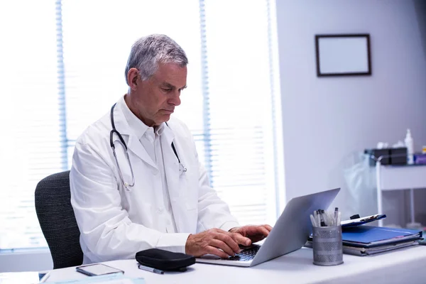 Lékař sedí u stolu a používání notebooku — Stock fotografie