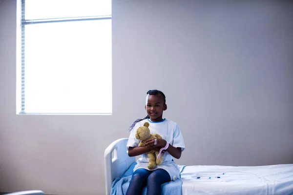 Пациент сидит на кровати с плюшевым мишкой — стоковое фото