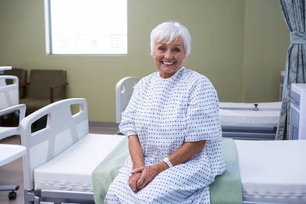 Paciente sênior sorrindo sentado na cama no hospital — Fotografia de Stock