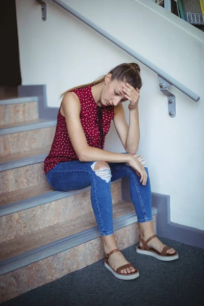 Sad schoolgirl sitting alone on staircase — Stock Photo, Image