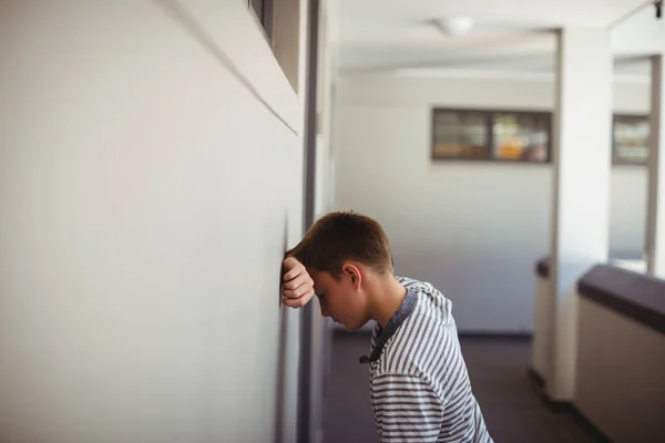 Sad schoolboy leaning head against wall — Stock Photo, Image