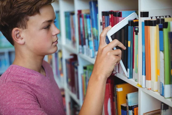 Студент тримає цифровий планшет у книжковій полиці — стокове фото