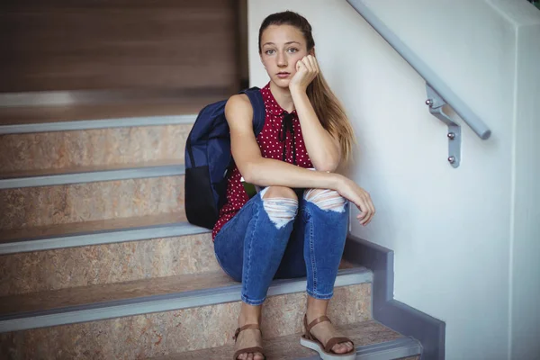 Sad schoolgirl sitting alone on staircase — Stock Photo, Image
