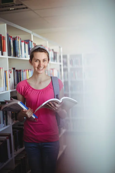 Estudante segurando livro na biblioteca — Fotografia de Stock