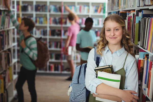Школярка тримає книги в бібліотеці — стокове фото