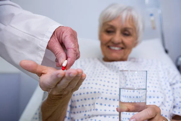 Doctor giving medicine pill to senior patient — Stock Photo, Image