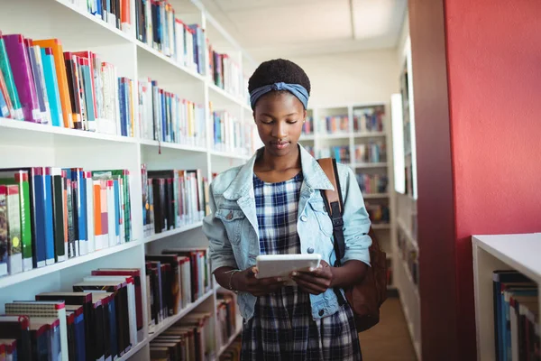 Attente schoolmeisje met behulp van digitale tablet in bibliotheek — Stockfoto