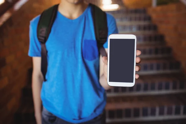 Školák stojící Schoolbag ukazující telefon — Stock fotografie