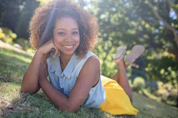 Uśmiechnięta kobieta, leżąc na trawie — Zdjęcie stockowe