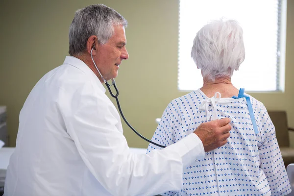 Médico examinando paciente sênior com estetoscópio — Fotografia de Stock