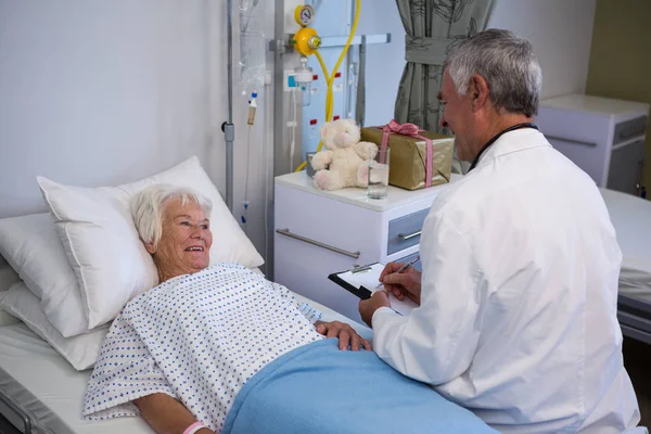 Врач обсуждает медицинское заключение со старшим пациентом — стоковое фото