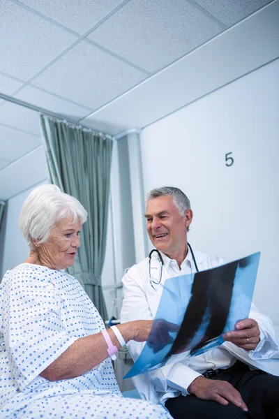 Doctor discutiendo informe de rayos X con paciente — Foto de Stock