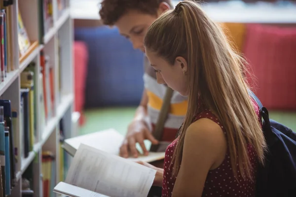 Attenti compagni di classe che leggono libro in biblioteca — Foto Stock